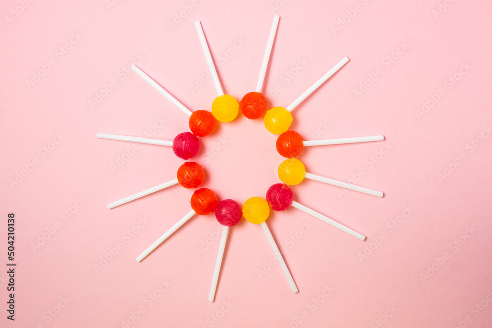 Lollipops are laid out in the shape of a circle on a pink background. Various fruit candies. sweet treat Lollipops are laid out in the shape of a circle on a pink background. Various fruit candies. sweet treat