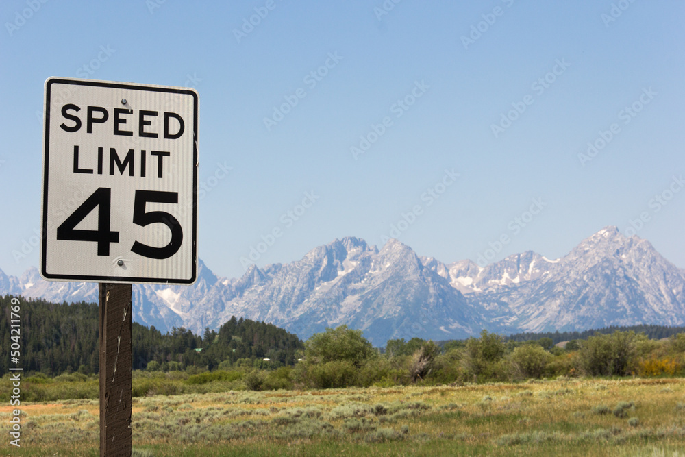Verkehrsschild in Amerika mit Tempolimit fünfundvierzig.
Verkehrszeichen in Front einer Gebirgskette aus dem National Park Great Teton in den USA.