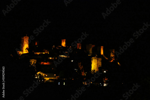 Night view on Mestia with its beautiful illuminated Svan Towers in the High Caucasus, Svaneti Region in Georgia. The moon is shinning on the tower, creating a a mysterious amosphere. Travel. Rural. photo