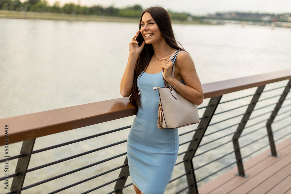 Young woman using a mobile phone while walking on the river promenade Young woman using a mobile phone while walking on the river promenade