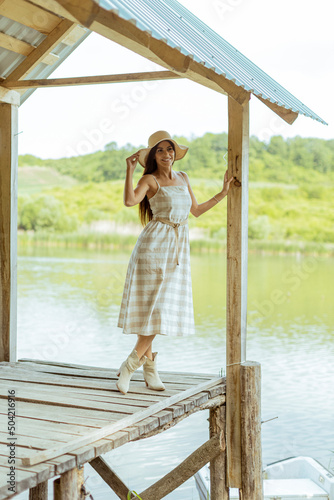 Young woman standing on the wooden pier at the calm lake