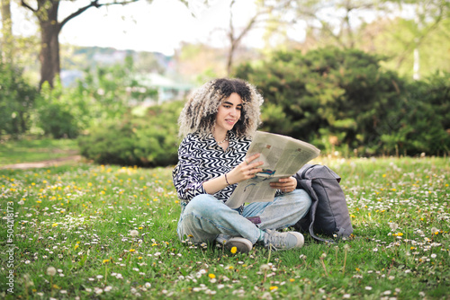 young woman witha  newspaper in a park photo
