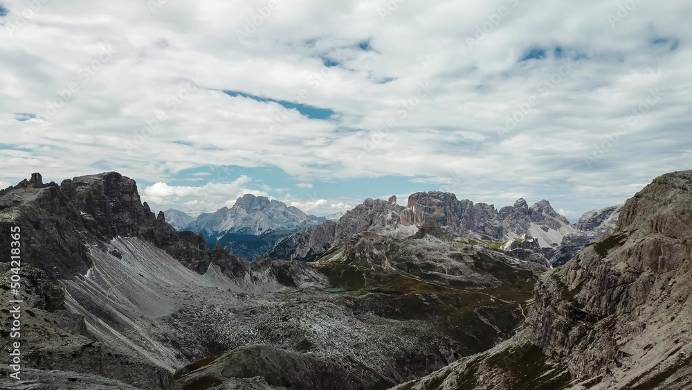 A panoramic view on Italian Dolomites. There are many high and sharp peak in front, with many landslides. Dangerous climbing. Barely any plants growing in the  area. Raw and unspoiled landscape.