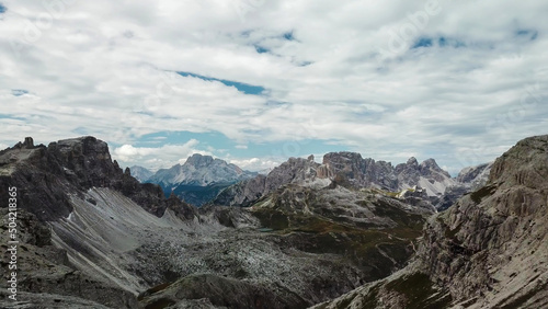 A panoramic view on Italian Dolomites. There are many high and sharp peak in front, with many landslides. Dangerous climbing. Barely any plants growing in the area. Raw and unspoiled landscape.