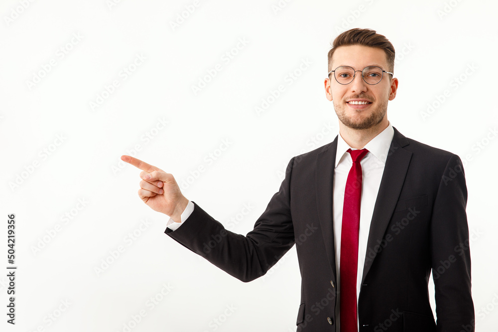 A young businessman in a business suit points to copyspace. A young businessman in a business suit points to copyspace.