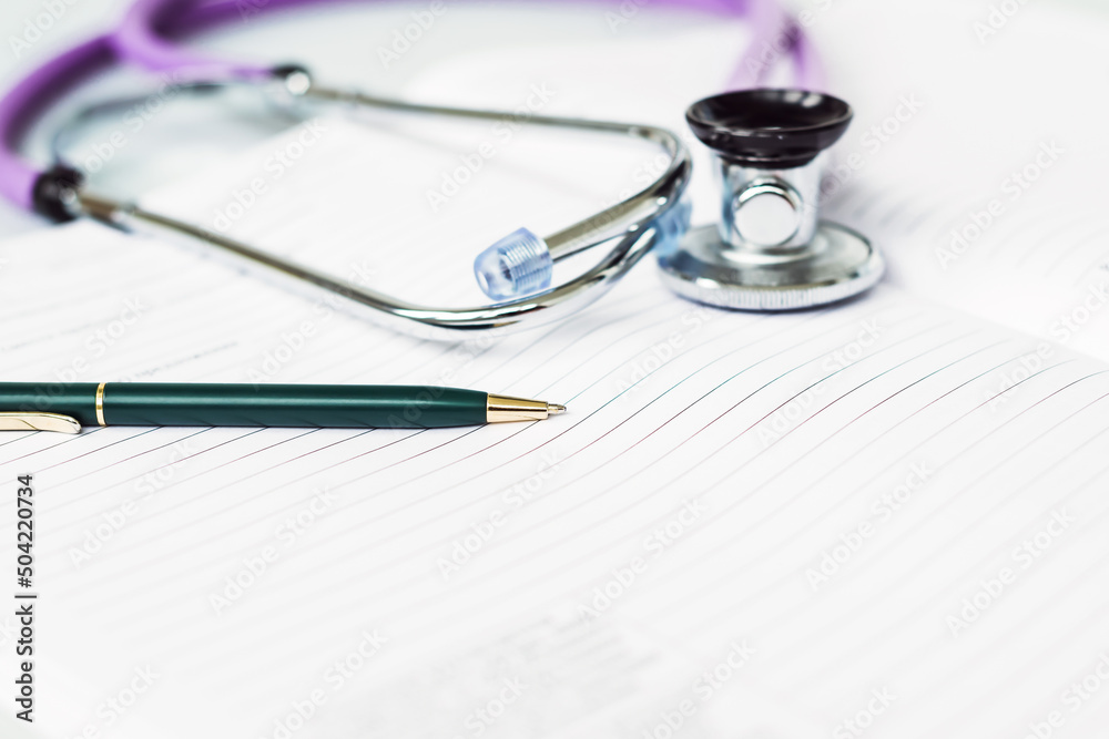Stethoscope in the office of doctors.Top view of doctor's desk table, blank paper on clipboard with pen. Copy space. Designer's blank Stethoscope in the office of doctors.Top view of doctor's desk table, blank paper on clipboard with pen. Copy space. Designer's blank
