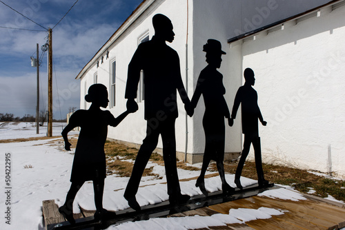 A metal depiction of a black family walking while holding hands and going toward a church Juneteenth