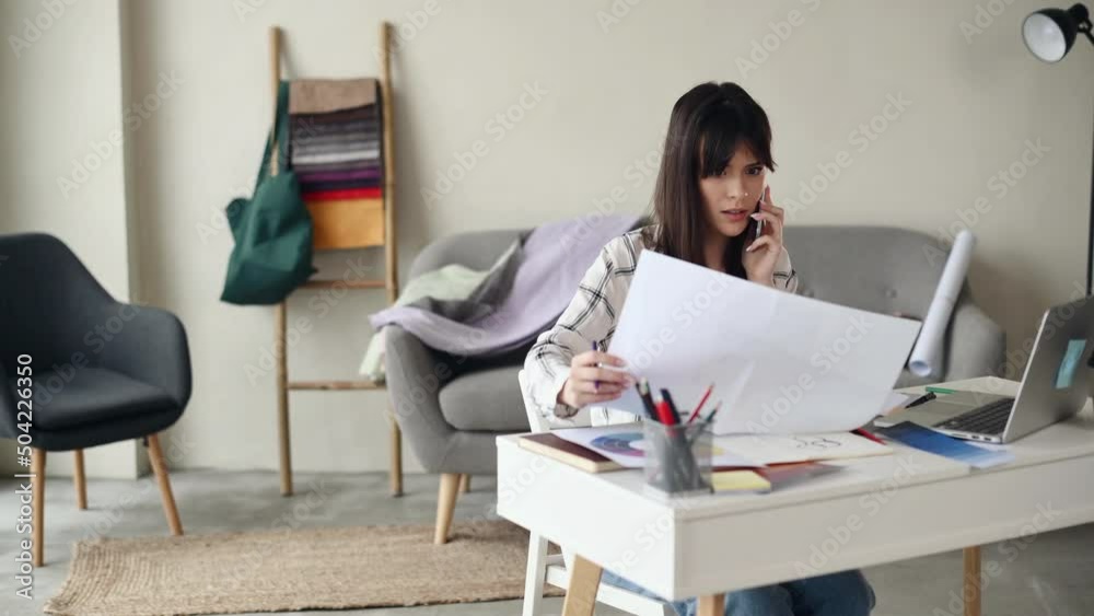 Sitting by the table. Young female designer working indoors Sitting by the table. Young female designer working indoors
