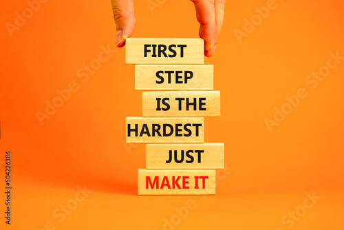 Make first step symbol. Wooden blocks with words First step is the hardest just make it. Beautiful orange table orange background. Businessman hand. Business and make first step concept. Copy space.