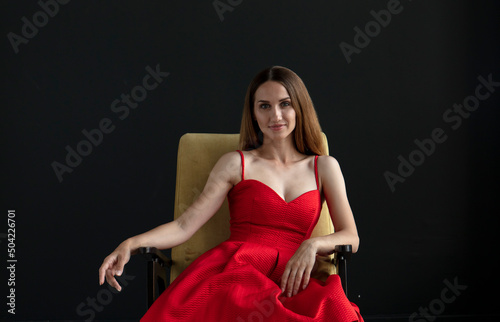 portrait of a young woman in a red dress sitting on a chair