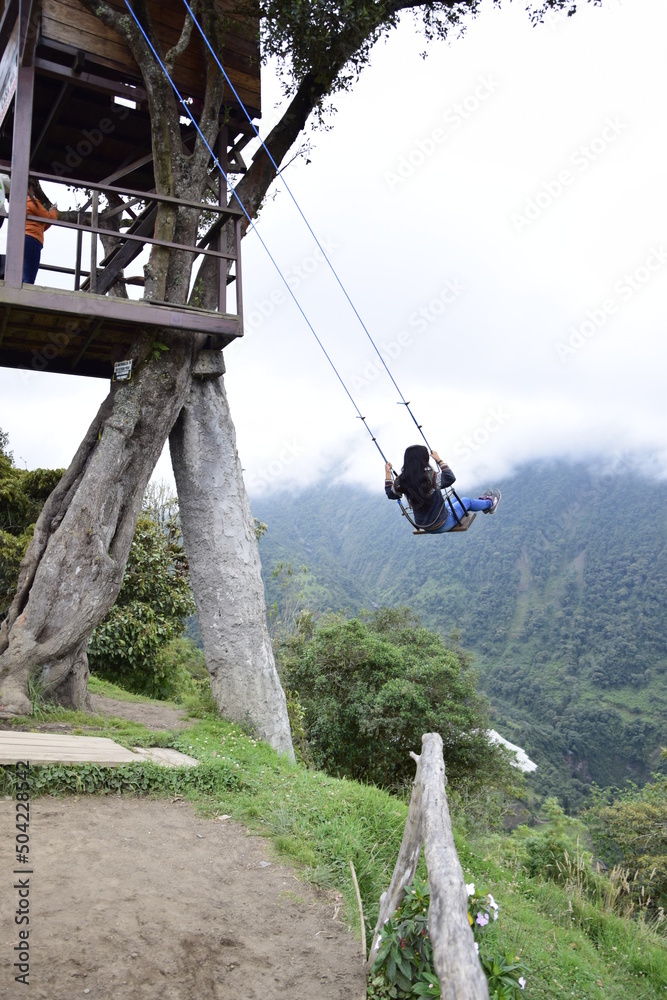 Obraz premium Tourist having fun swinging on Giant Swing. View of green mountains and trees in background. Banos
