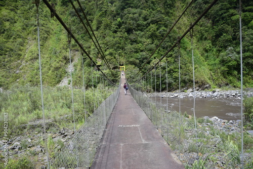 Suspension bridge across the river near by Cascada Manto de la Novia, waterfall in Banos de Agua Santa, Banos