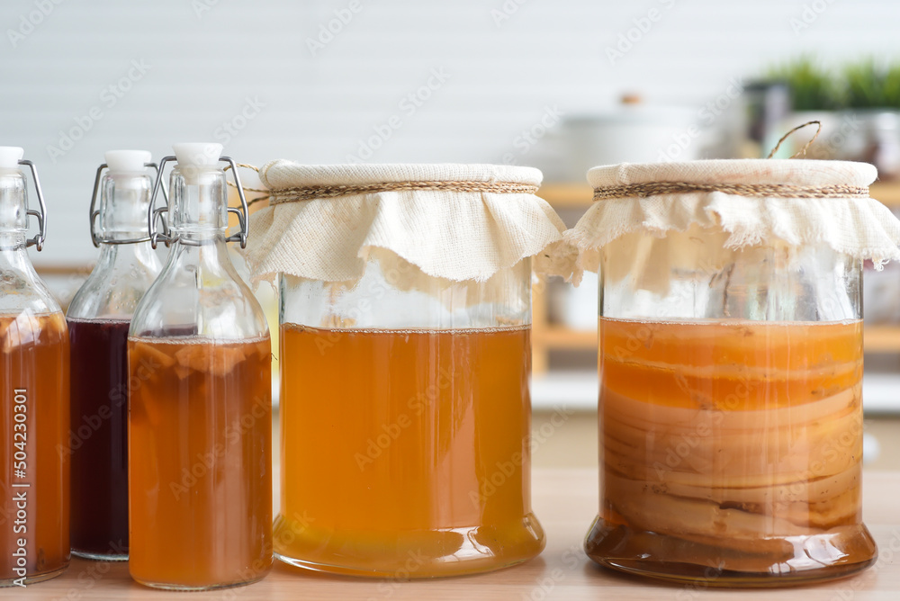 Homemade fermented raw kombucha tea, variety of flavors in bottles and glass jars mix with a fruit juice and scoby on wooden table. Healthy natural probiotic drink. Homemade fermented raw kombucha tea, variety of flavors in bottles and glass jars mix with a fruit juice and scoby on wooden table. Healthy natural probiotic drink.