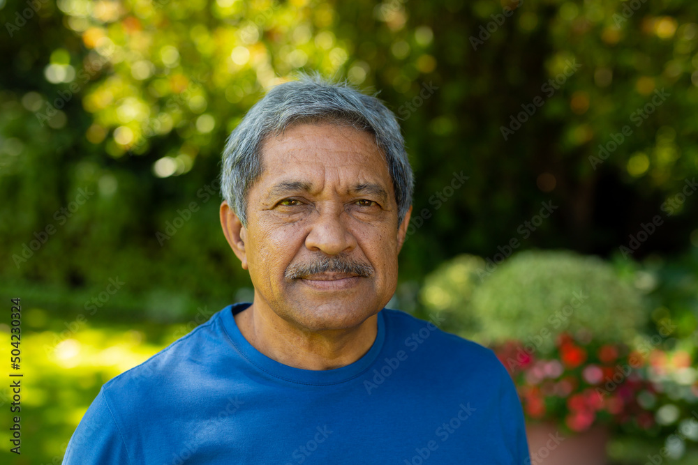 Close-up portrait of confident biracial senior man wearing sports clothing against plants in yard Close-up portrait of confident biracial senior man wearing sports clothing against plants in yard