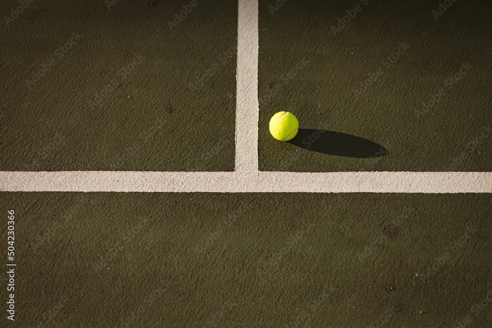 High angle view of yellow tennis ball by white lines at tennis court during sunset, copy space