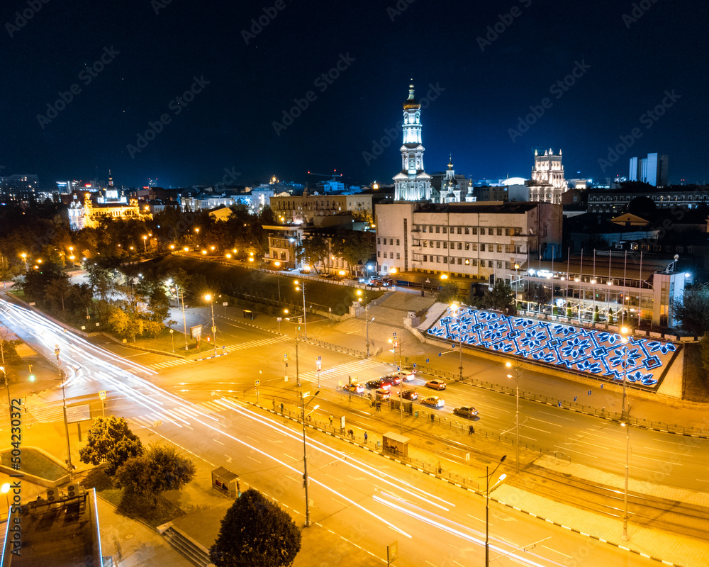 Night city center streets with cars driving in long exposure. Aerial view on Dormition Cathedral with illumination. Downtown streets in Kharkiv, Ukraine