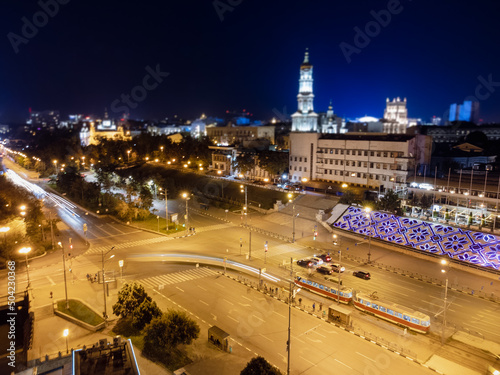 Night city center streets with tram and cars driving in long exposure. Aerial view on Dormition Cathedral with illumination. Downtown streets in Kharkiv, Ukraine