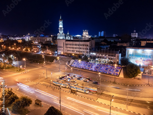 Aerial view on night city center streets with tram and cars driving in long exposure. Dormition Cathedral with illumination. Downtown streets in Kharkiv, Ukraine