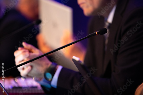 focus sur un micro et les mains d'un orateur prononçant un discours à la tribune lors d'un meeting politique, d'un colloque ou d'une réunion photo