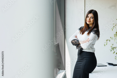 Happy young handsome business woman standing in her office. Confident business woman