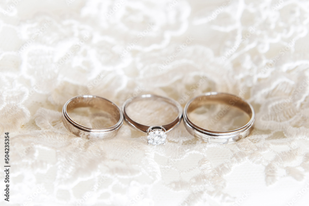 Wedding rings with a diamond on wedding dress background Wedding rings with a diamond on wedding dress background