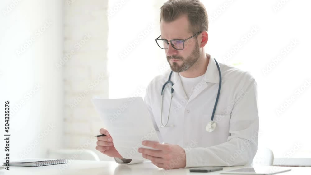 Doctor Reading Documents while Sitting in Office Doctor Reading Documents while Sitting in Office