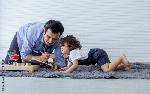 Caucasian handsome happy father teaching, drawing, playing toys together with his little cute daughter at home after work. Family, Kids and Education Concept.