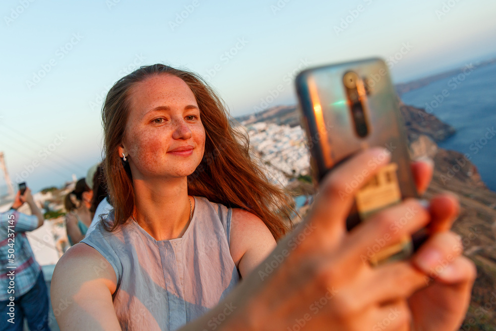 The girl making selfie on Santorini island background.