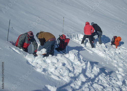 Bild auf Leinwand Avalanche safety students digging snow pits to test slope stability during high