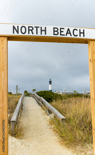 North Beach Sign and Boardwalk on North Beach With Historic Tybee Island Light Station, Tybee Island, Georgia, USA
