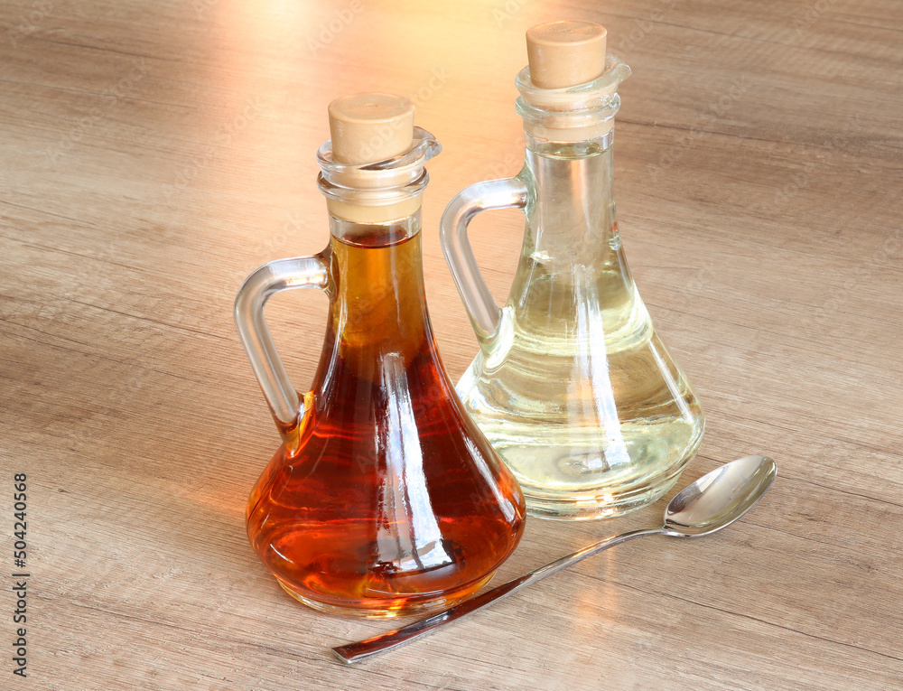 Bottles with vegetable oil (olive, sunflower or linseed) and a spoon for oil on a wooden table Bottles with vegetable oil (olive, sunflower or linseed) and a spoon for oil on a wooden table