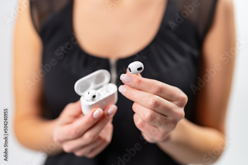 Wireless earphone in woman hands. Young lady holding earbuds.