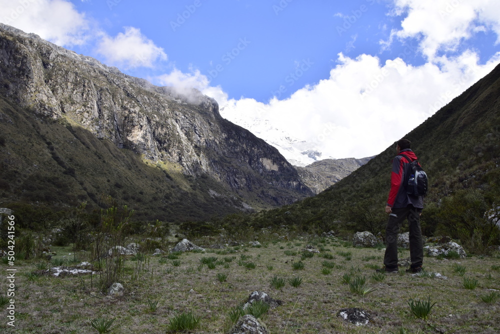 A tourist with a backpack looks at the mountains on the way to Lagoon 69. Huascaran National Park in the Sands of Peru