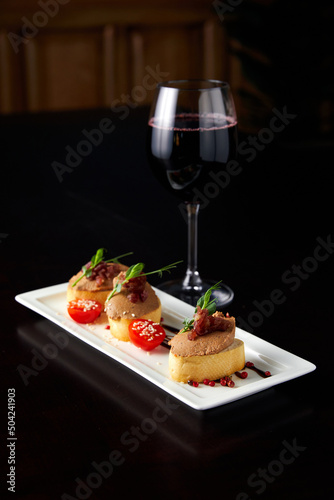 Glass with wine and toasts with delicious paste on table