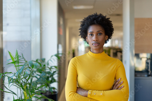 Portrait of confident young african american businesswoman with arms crossed at modern workplace