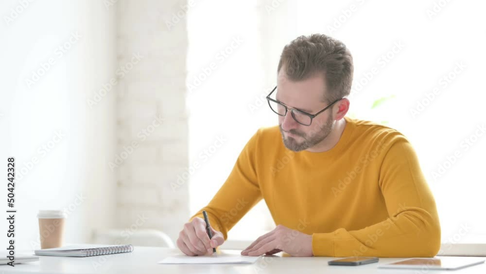 Man Writing on Paper in Office Man Writing on Paper in Office