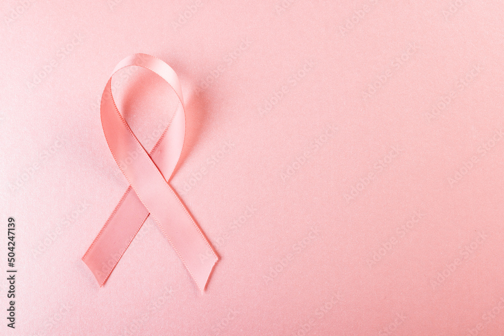 Close-up of pink breast cancer awareness ribbon isolated against pink background, copy space Close-up of pink breast cancer awareness ribbon isolated against pink background, copy space