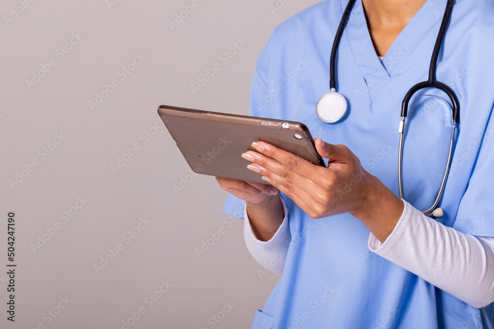 Midsection of african american mid adult female doctor using digital pc against white background