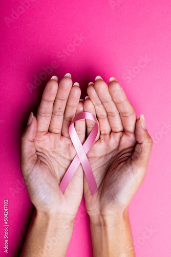 Hands of african american mid adult woman holding pink breast cancer awareness ribbon, copy space