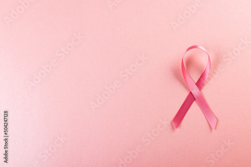 Directly above shot of pink breast cancer awareness ribbon over pink background, copy space