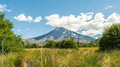 Volcano in the background and meadows surrounding it on a sunny day in Lanin National Park. Argentina