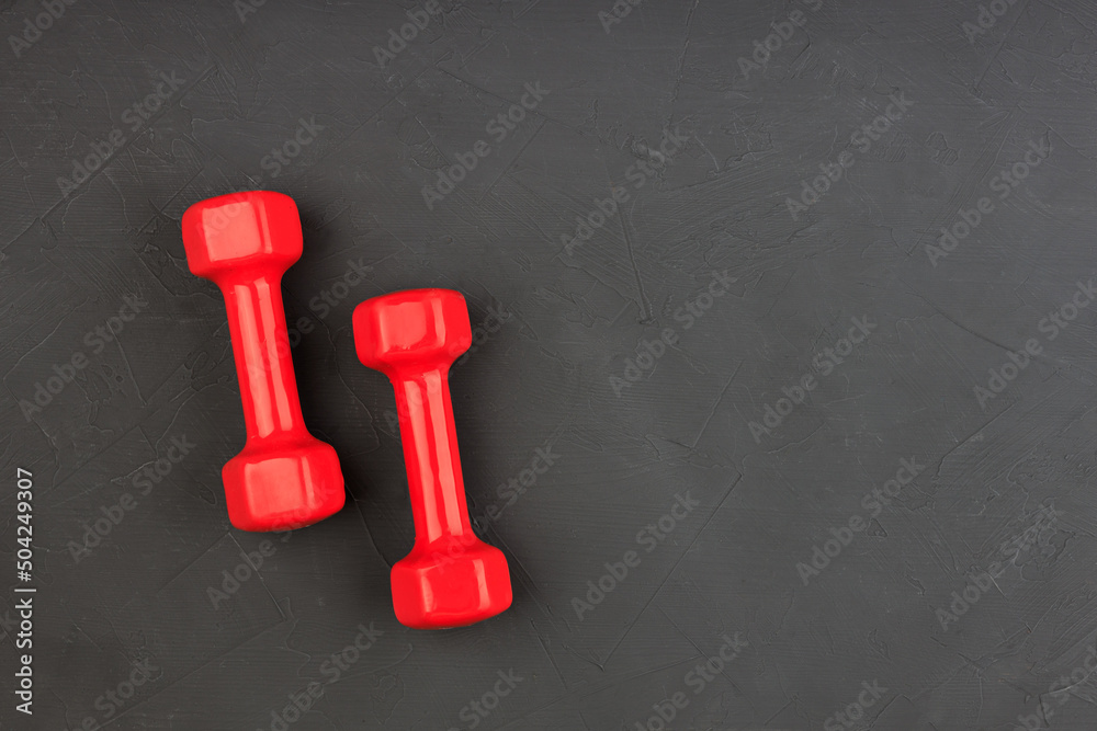 two red dumbbells in the corner of a black background two red dumbbells in the corner of a black background