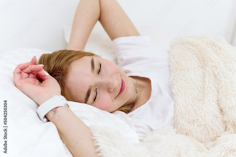 Peaceful beautiful young lady lying, relaxing, sleeping in cozy white bed on soft pillow resting covered with blanket enjoying good healthy sleep concept Peaceful beautiful young lady lying, relaxing, sleeping in cozy white bed on soft pillow resting covered with blanket enjoying good healthy sleep concept