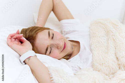 Peaceful beautiful young lady lying, relaxing, sleeping in cozy white bed on soft pillow resting covered with blanket enjoying good healthy sleep concept