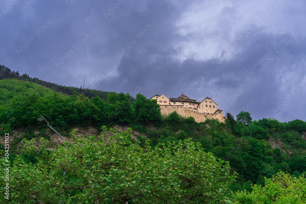 Lonely castle in the forest on a mountain above the city of Vaduz in the Principality of Liechtenstein on an overcast spring evening against a dramatic cloudy sky, Europe travel backdrop
