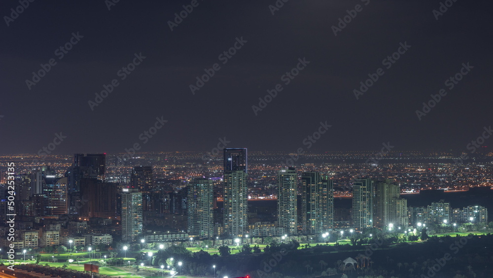 Moon rising over greens and al barsha heights district area night timelapse from Dubai marina.