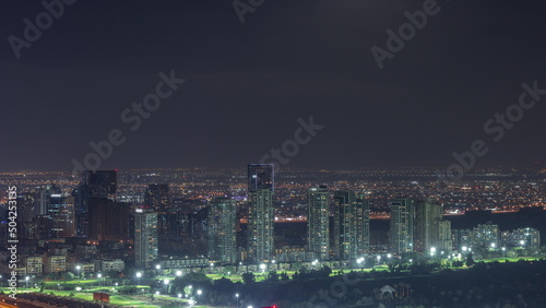 Moon rising over greens and al barsha heights district area night timelapse from Dubai marina.