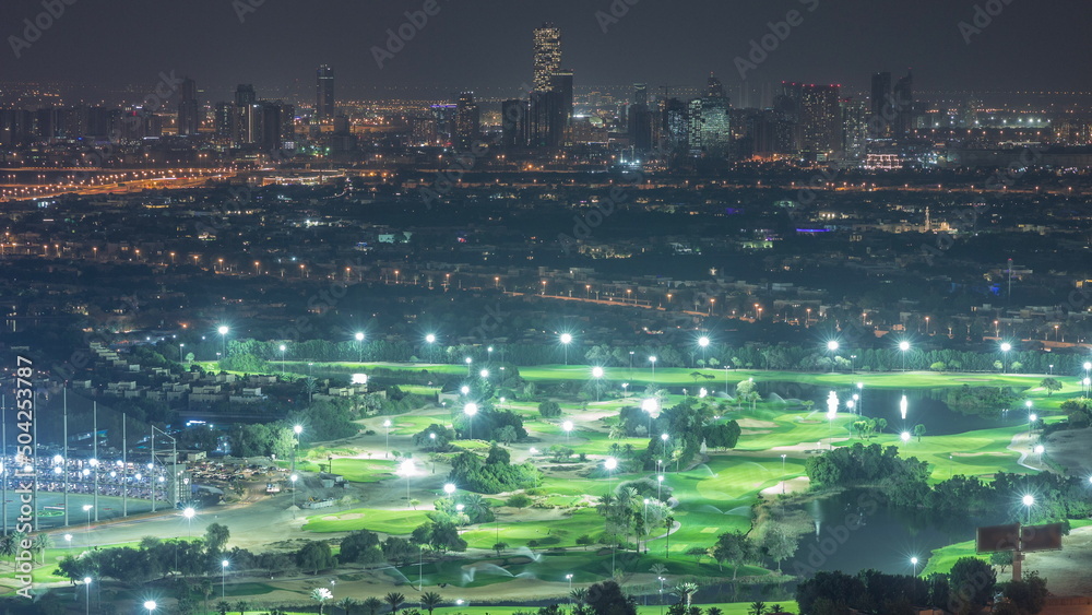 Aerial view to Golf course with green lawn and lakes, villa houses behind it night timelapse.