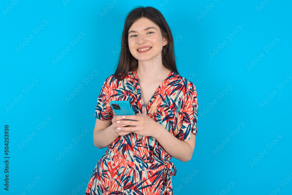 young caucasian woman wearing floral dress over blue background Mock up copy space. Using mobile phone, typing sms message young caucasian woman wearing floral dress over blue background Mock up copy space. Using mobile phone, typing sms message