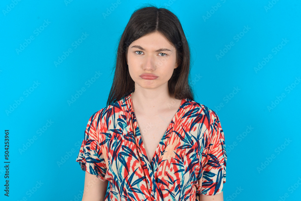 young caucasian woman wearing floral dress over blue background depressed and worry for distress, crying angry and afraid. Sad expression. young caucasian woman wearing floral dress over blue background depressed and worry for distress, crying angry and afraid. Sad expression.